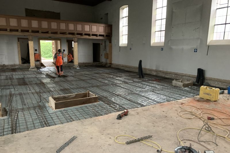 In einem leeren, mit Betonstahl verstärkten Gebäude bereiten Arbeiter den Boden für das Betonieren vor und demonstrieren die Präzision der Hochbau-Techniken.