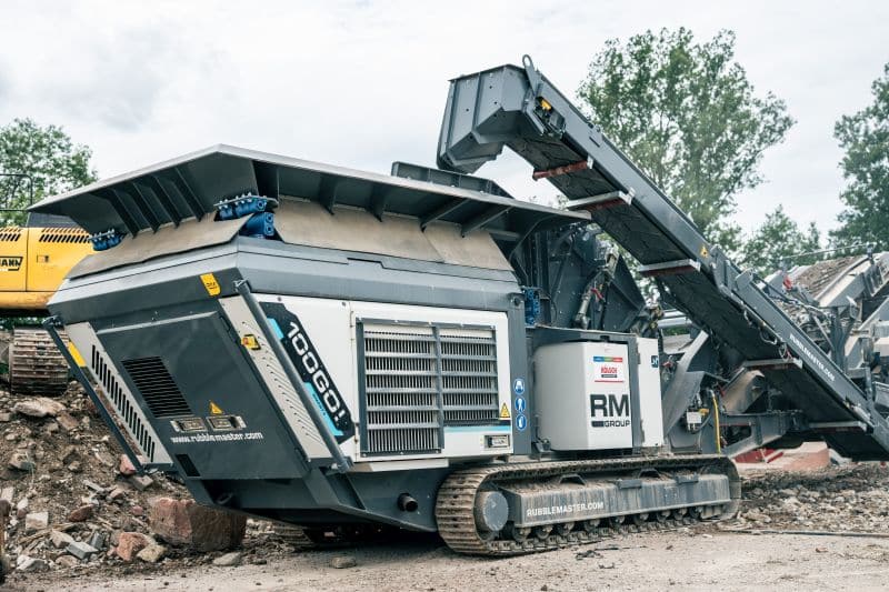 Nahaufnahme einer großen mobilen Industriebrechermaschine auf einer Hochbau-Baustelle, umgeben von Trümmern.